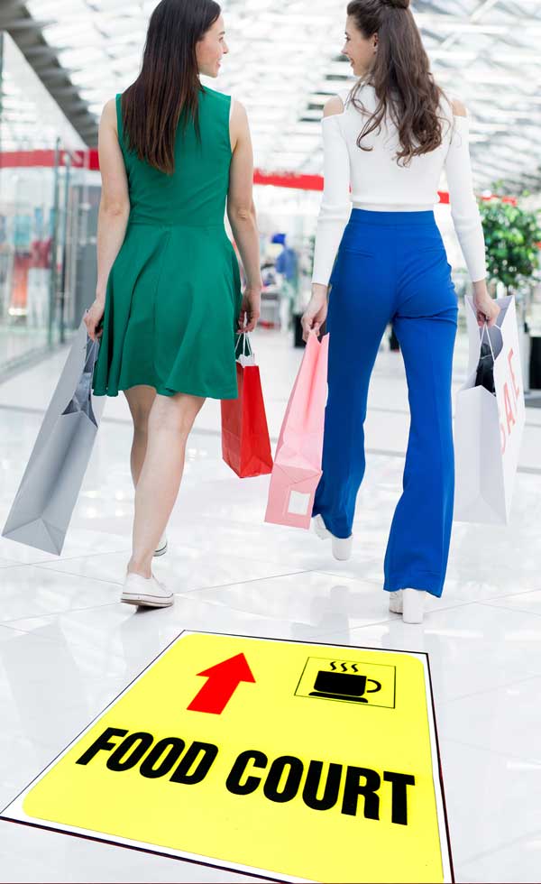 Floor graphics guiding two women to a food court