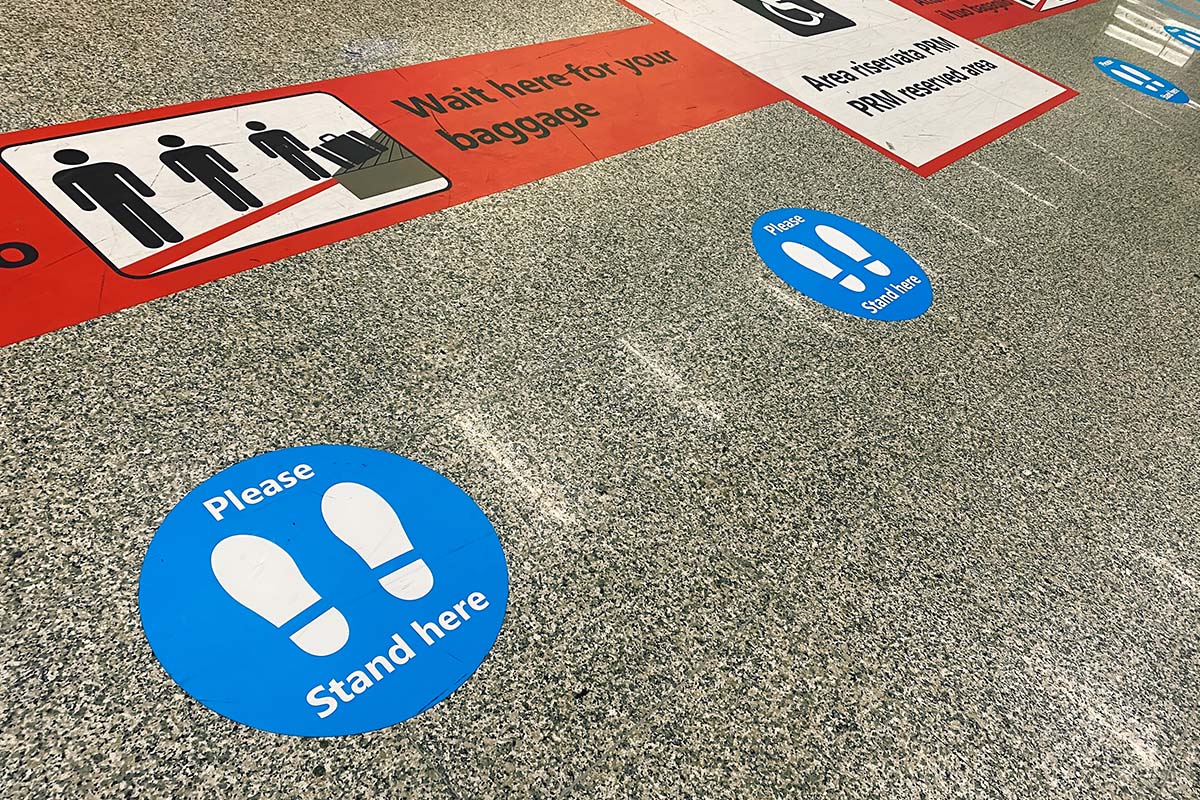 Universal_Sign_and_Graphics_Sign_Gallery_COVID 19_Signs__0007_stickers-on-the-floor-near-the-baggage-claim-belt-at-the-airport